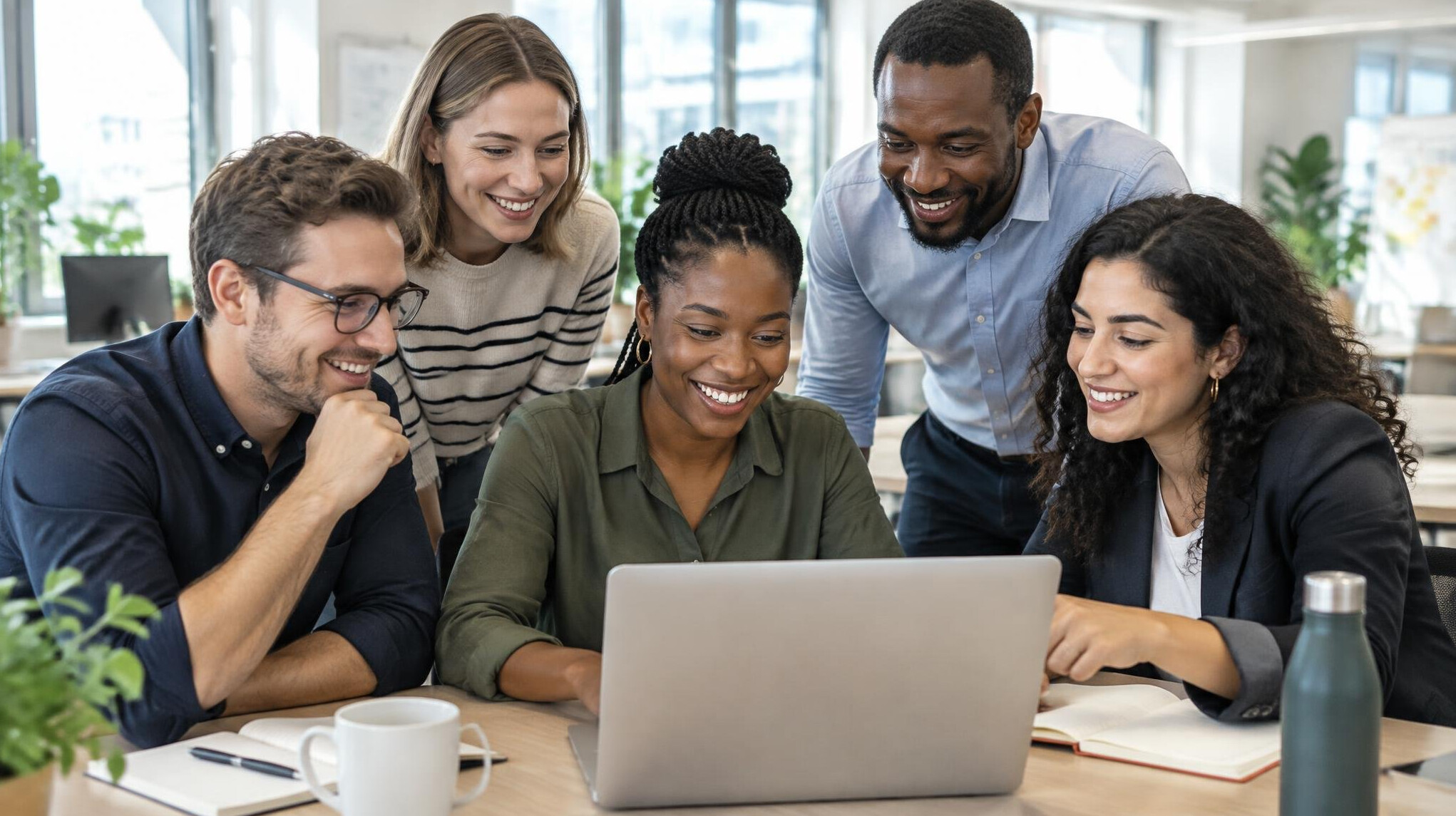 Colleagues collaborating around a laptop